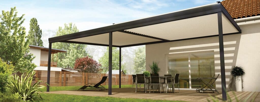 Cette image montre une grande pergola en bois blanc qui s'étend le long d'un jardin. Elle est entourée de buissons et de fleurs luxuriants, avec des murs blancs derrière elle. La structure est couverte de plantes grimpantes qui lui donnent une atmosphère romantique et mystérieuse. Des lumières suspendues à la pergola créent un éclairage doux et intime, tandis que des chaises bistrot confortables invitent les visiteurs à profiter du cadre enchanteur.