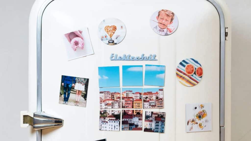 Réfrigérateur blanc au style vintage orné de photographies et d'aimants décoratifs.