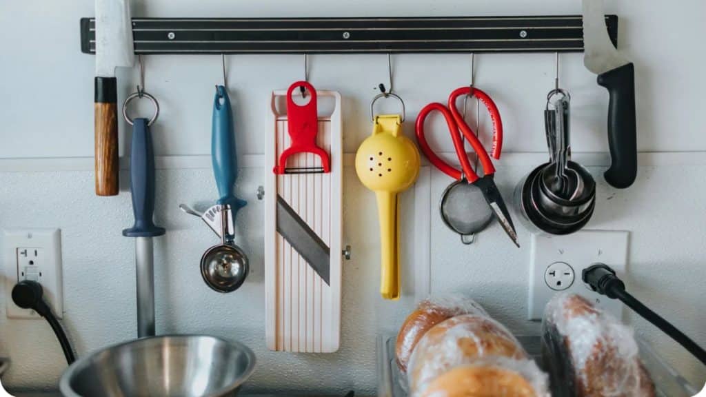 Barre magnétique murale avec couteaux, éplucheurs et ciseaux pour l'organisation d'une cuisine moderne.