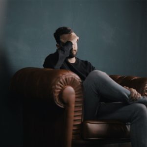 La personne semble anxieuse, car elle se tient la tête avec les mains et regarde le sol. Elle paraît très désemparée et désespérée, ce qui pourrait suggérer qu'elle fait face à des problèmes psychologiques intenses. On peut également deviner que cette personne souffre du syndrome de stress post-traumatique (SSPT).