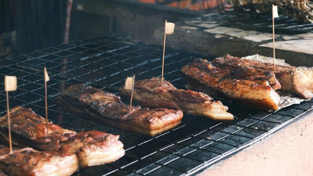 Morceaux de poitrine de porc sur une grille de fumoir lors du processus de fumage à chaud.